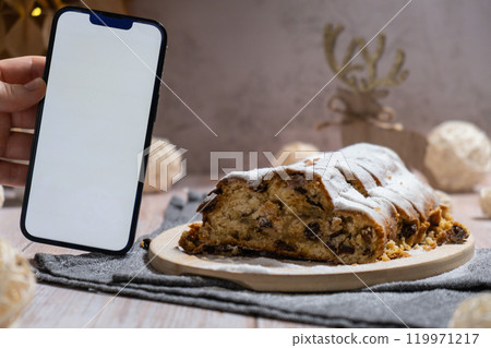 Homemade Christmas traditional cake pie with marzipan nuts and dried fruits pastry dessert stollen. Smartphone with white screen application website advertisement mock up template. Winter holidays Homemade Christmas traditional cake pie with marzipan nuts and dried fruits pastry dessert stollen. Smartphone with white screen application website advertisement mock up template. Winter holidays 119971217