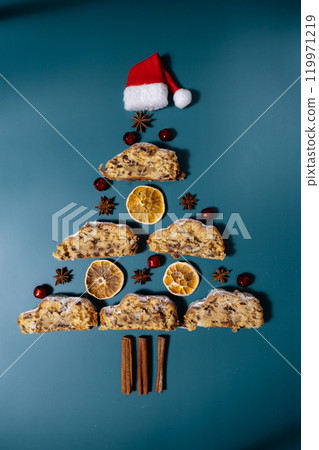 Christmas tree made of Slices of Homemade traditional cake pie with marzipan nuts and dried fruits pastry dessert stollen. Winter holidays season atmosphere. Creative minimalistic greeting card 119971219
