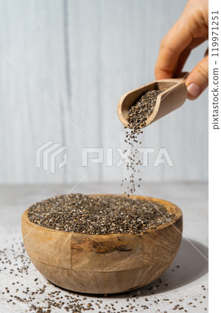 Chia seeds fall in wooden bowl. Healthy superfood rich in Omega 3 fatty acids. Dry healthy natural ingredient. Chia grains are falling Chia seeds fall in wooden bowl. Healthy superfood rich in Omega 3 fatty acids. Dry healthy natural ingredient. Chia grains are falling 119971251