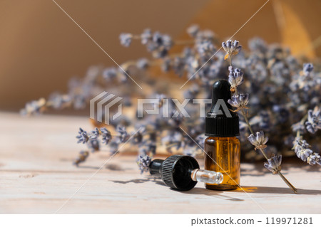 Lavender flowers with dropper glass bottle of essential oil. Concept of alternative medicine. Herbal natural detox treatment. Stress relief calming mental health products Lavender flowers with dropper glass bottle of essential oil. Concept of alternative medicine. Herbal natural detox treatment. Stress relief calming mental health products 119971281