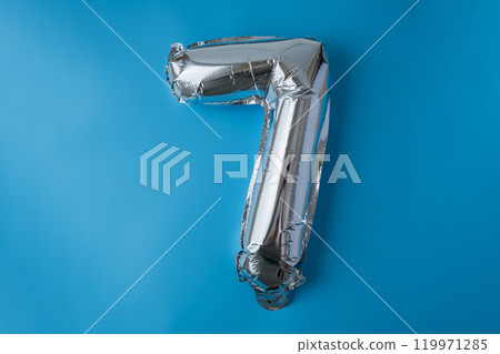 7 seven metallic balloon isolated on blue background. Greeting card silver foil balloon number Happy birthday holiday concept. Copy space for text. Celebration party congratulation 119971285