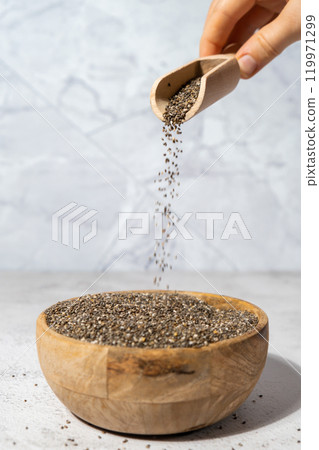 Chia seeds fall in wooden bowl. Healthy superfood rich in Omega 3 fatty acids. Dry healthy natural ingredient. Chia grains are falling Chia seeds fall in wooden bowl. Healthy superfood rich in Omega 3 fatty acids. Dry healthy natural ingredient. Chia grains are falling 119971299