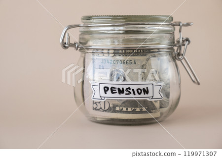 Glass jar full of American currency dollars cash banknote with text PENSION. Preparation saving money. Moderate consumption and economy Glass jar full of American currency dollars cash banknote with text PENSION. Preparation saving money. Moderate consumption and economy 119971307