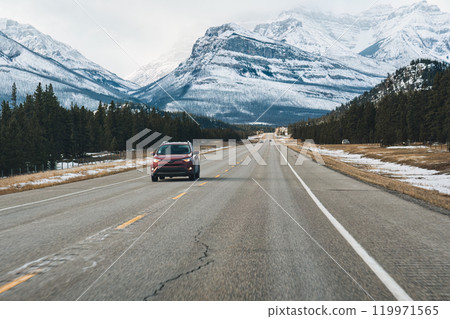 Road trip with on highway road with snow covered rocky mountains in winter at Kootenay plains area, Canada 119971565