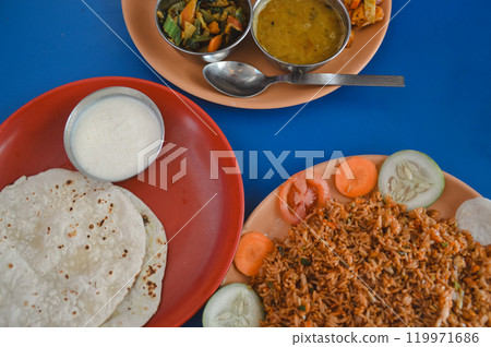Overhead view of dal bhat tarkari set or rice and lentil soup, chicken biryani, juju dhau or yogurt and roti, authentic local Nepalese daily staple food 119971686