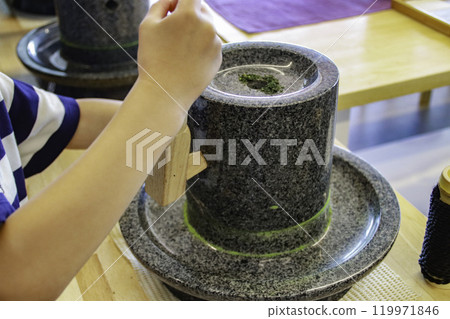 Child grinding matcha with a stone mill (7 years old/boy) 119971846