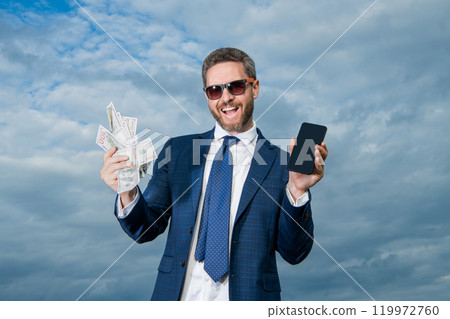 cheerful betting man with lottery money outdoor. betting man with lottery money hold phone. 119972760