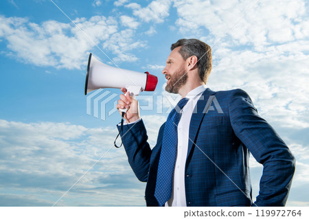 businessman shout in loudspeaker on sky background 119972764