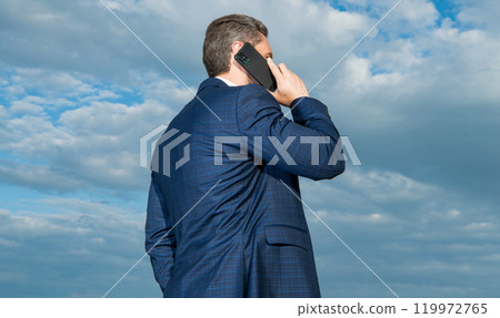 back view photo of man having phone talk. man has phone talk on sky background. back view photo of man having phone talk. man has phone talk on sky background. 119972765