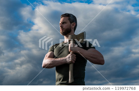 strong man with axe. caucasian woodsman man hold ax. brutal man on sky background strong man with axe. caucasian woodsman man hold ax. brutal man on sky background 119972768