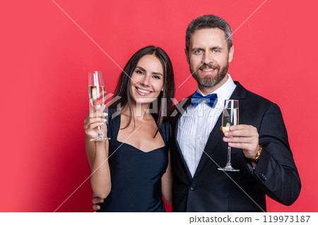 Romantic date celebrations. Valentines day. Celebrate anniversary. Couple in love celebrate engagement. Elegant couple drink champagne isolated on red. Couple at formal occasion. Festive couple 119973187