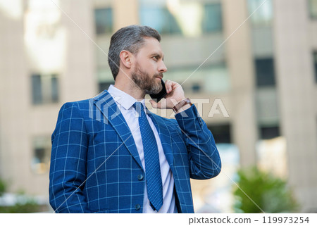 Businessman in front office. Social network. Hispanic business man with phone at office building. Businessman using phone. Man phone conversation in city. Businessman employee talking on phone Businessman in front office. Social network. Hispanic business man with phone at office building. Businessman using phone. Man phone conversation in city. Businessman employee talking on phone 119973254