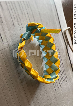 Close up of a yellow and blue Ukrainian ribbon bow on a book. Close up of a yellow and blue Ukrainian ribbon bow on a book. 119973371