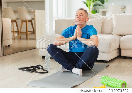Yoga mindfulness meditation. Senior adult mature man practicing yoga at home. Mid age old grandfather sitting in lotus pose on yoga mat meditating relaxing. Older man doing breathing practice 119973732