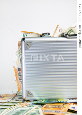 A silver aluminum suitcase overflowing with US Dollar and Euro banknotes A silver aluminum suitcase overflowing with US Dollar and Euro banknotes 119974265