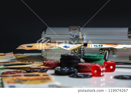 An open aluminum case with Euro bills and stacks of poker chips scattered around it An open aluminum case with Euro bills and stacks of poker chips scattered around it 119974267