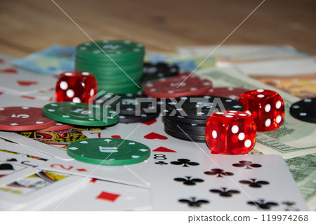 Red dice, green and black poker chips, and playing cards on euro bills Red dice, green and black poker chips, and playing cards on euro bills 119974268