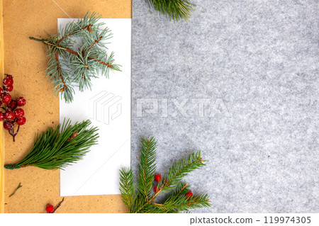 Festive holiday decorations with greenery and berries arranged on a textured gray background during the winter season Festive holiday decorations with greenery and berries arranged on a textured gray background during the winter season 119974305