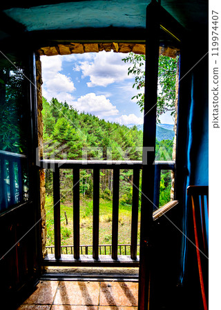 View from the window of a rustic house towards a beautiful landscape of mountains, trees and nature 119974407