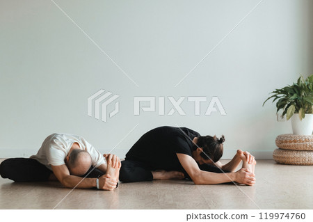 two young athletes practice yoga in the gym. Joint training, indoors, studio. The concept of a healthy lifestyle 119974760