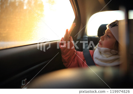 a child sitting in a car, gazing thoughtfully out the window. The soft light illuminates the child's face, highlighting a sense of wonder and curiosity as they observe the world passing by. a child sitting in a car, gazing thoughtfully out the window. The soft light illuminates the child's face, highlighting a sense of wonder and curiosity as they observe the world passing by. 119974826