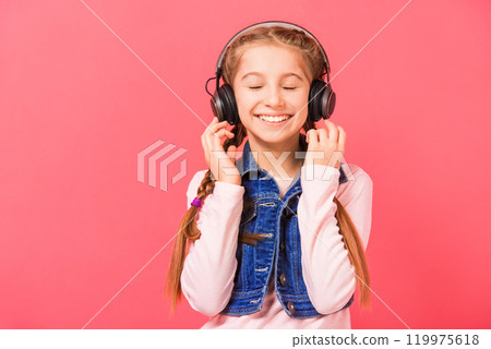 Cute young teen girl enjoying listening to music in wireless headset over rose background Cute young teen girl enjoying listening to music in wireless headset over rose background 119975618