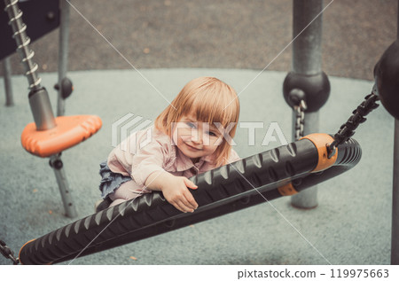 cute little girl on a swing on playground cute little girl on a swing on playground 119975663
