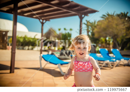 little cheerful girl running around the pool little cheerful girl running around the pool 119975667