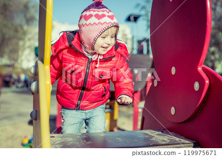 little cute girl playing at the playground in autumn 119975671