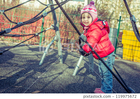 little cute girl playing at the playground in autumn 119975672