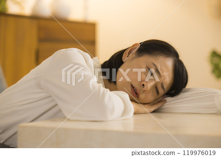 Middle-aged woman in the living room at night Middle-aged woman in the living room at night 119976019