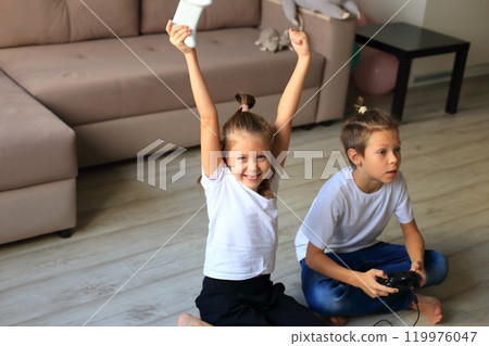 A lively scene of a boy and girl enthusiastically playing video games together at home. they immerse themselves in the gaming experience, highlighting the joy of childhood and the importance of 119976047