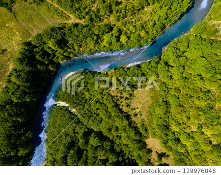 Aerial view of a serene winding river flowing through lush green forested landscape, perfect for nature lovers and adventurers. Aerial view of a serene winding river flowing through lush green forested landscape, perfect for nature lovers and adventurers. 119976048