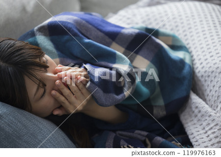 Woman feeling unwell in living room in winter Woman feeling unwell in living room in winter 119976163