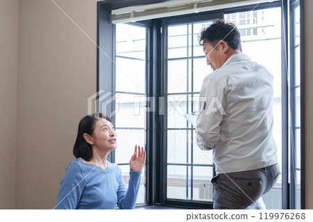 A repairman and a customer inspecting a window sash 119976268