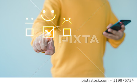 Customer hand touch a virtual screen showing a happy smile icon, indicating service satisfaction. Business concept involves assessment, customer service testimonials, and feedback, rated very good. 119976734