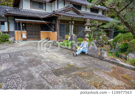 Woman gardening an old house - Country living 119977563