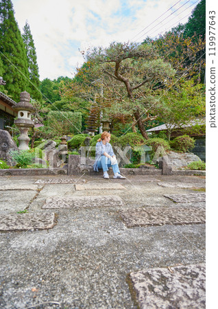 Woman gardening an old house - Country living 119977643