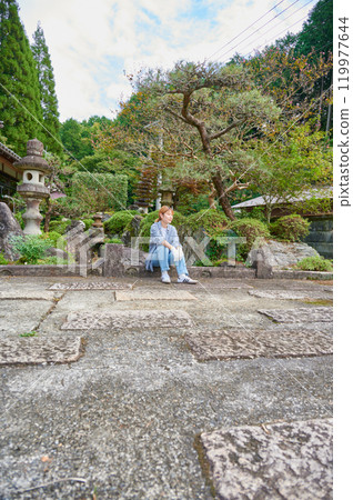Woman gardening an old house - Country living 119977644