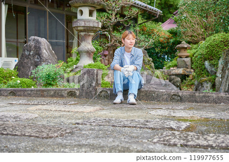 Woman gardening an old house - Country living Woman gardening an old house - Country living 119977655