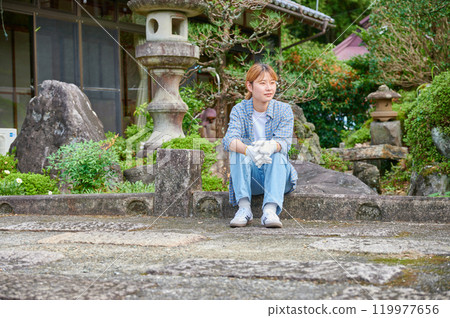 Woman gardening an old house - Country living Woman gardening an old house - Country living 119977656