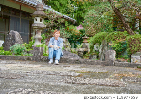 Woman gardening an old house - Country living 119977659