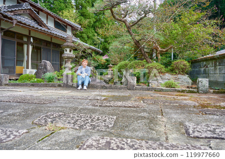 Woman gardening an old house - Country living Woman gardening an old house - Country living 119977660