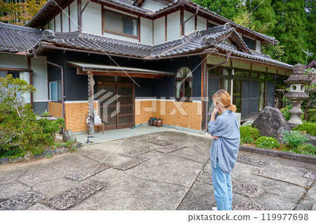 一個女人在古老的民居、空置的房子、遺產、鄉村前歪著頭 119977698