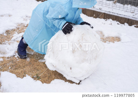 Boy rolling snow 119977805
