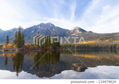 Tranquil lake waters at the mountain foot in autumn forest. 119979620