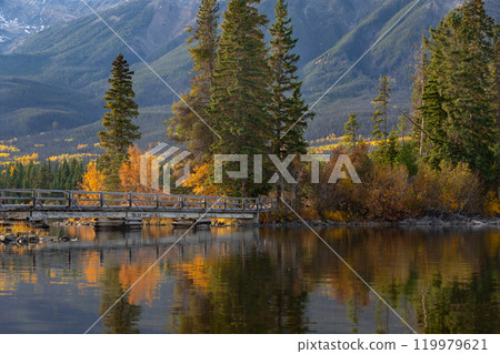 Wooden bridge across the lake to the little island in mountains. 119979621