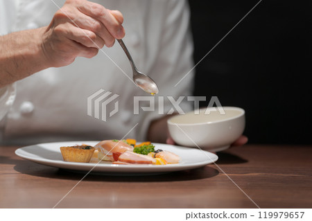 The hands of a male chef arranging food 119979657
