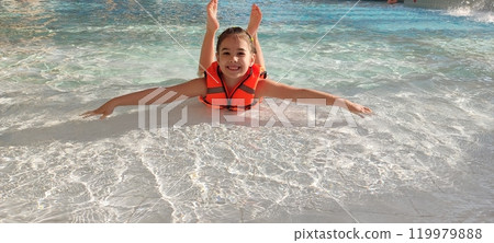 Joyful child floating in pool with bright orange life vest Joyful child floating in pool with bright orange life vest 119979888