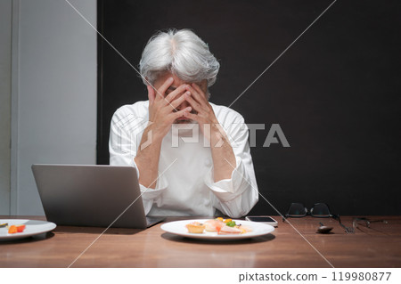 A chef improves a dish by looking at a computer A chef improves a dish by looking at a computer 119980877